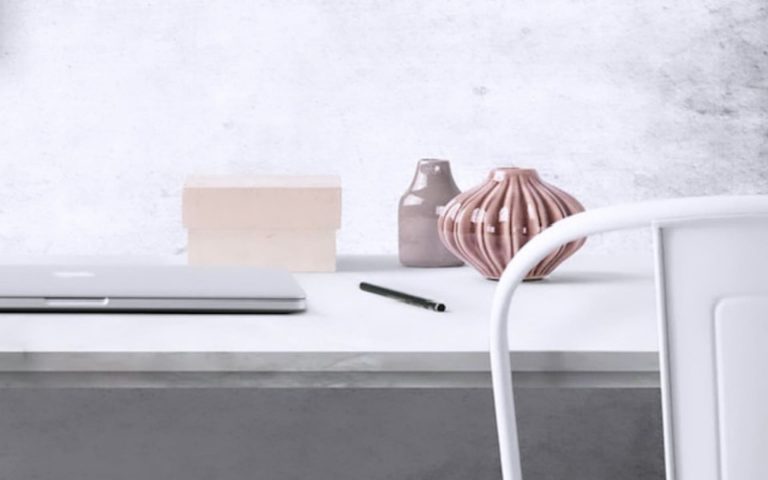 Photographie d'un bureau avec un ordinateur, un crayon et deux vases de décoration